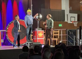 Bernhard Feineisen (Mitte), Leiter des Amtes für Bildung und Kultur, erlebt bei einem von Thomas Müller (links) und Felix Bold durchgeführten Experiment hautnah, wie 700.000 Volt einen kleinen Propeller auf seinem Helm in Bewegung setzen. Foto: Nina Tossenberger